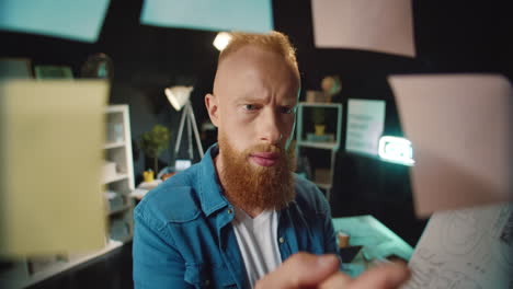 un hipster confundido tratando de elegir la pegatina correcta en el tablero de trabajo en la oficina oscura.