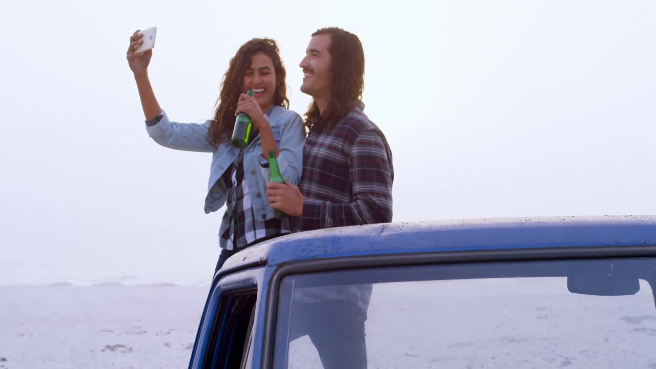 pareja tomando una selfie con el teléfono móvil mientras beben cerveza 4k