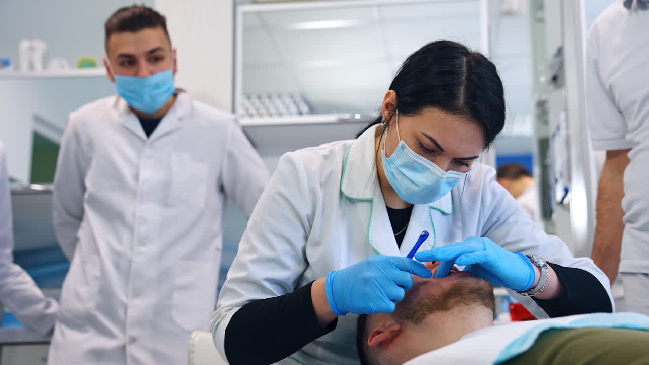 Focused female student wearing latex gloves working in patient's mouth. Future dentist practices tightening the braces.