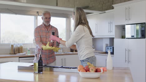 Middle-aged-caucasian-couple-cleaning-kitchen-at-home,-slow-motion