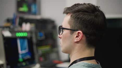 close-up of male broadcast operator sitting at control panel, managing live television broadcast. operator focuses on camera transitions, adjusting control board. focused on production process