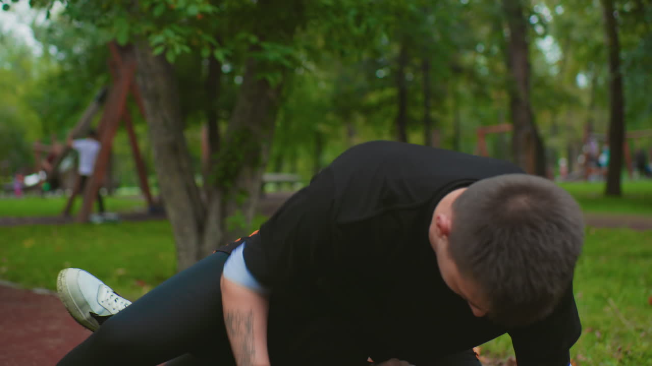 white male coach holding pads in park, focused mitt training under trees, student throwing measured punches, clinch and takedown practice, gloves, sweat, determination, evening green backdrop, urban