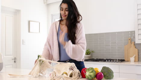 indian woman unpacking fresh vegetables in modern kitchen, preparing healthy meal