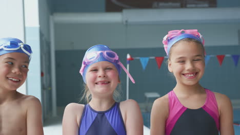 Portrait-Of-Children-Standing-By-Edge-Of-Swimming-Pool-For-Lesson