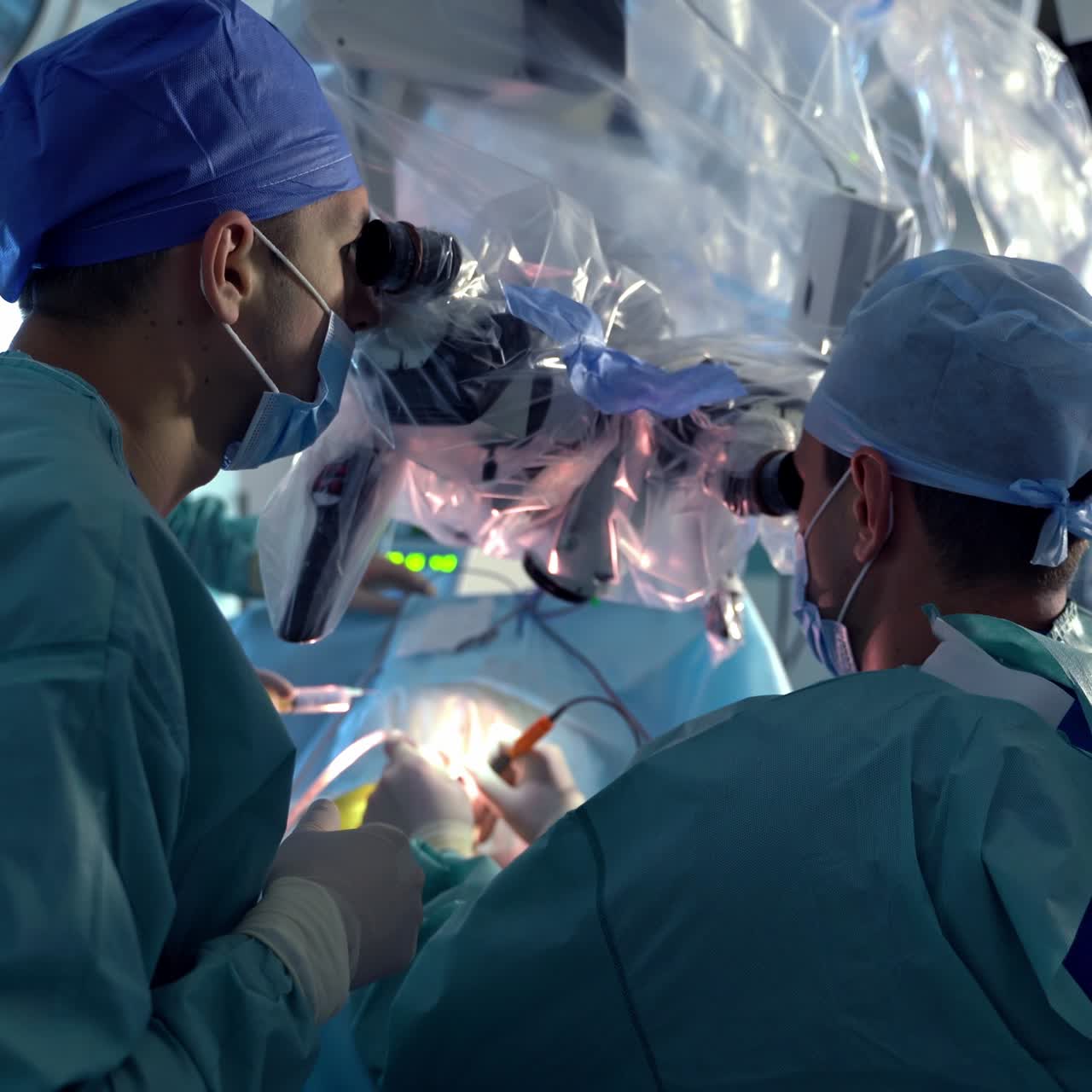 Doctors monitoring neurosurgical operation through the microscope. High-precise surgical work conducted by professional medical care team