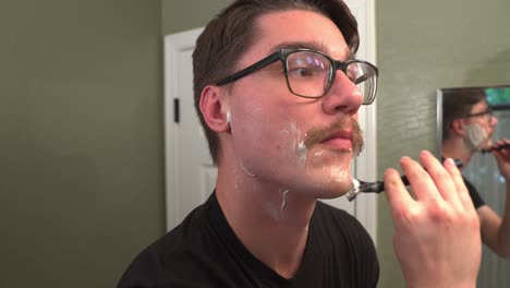 man with glasses and mustache shaving