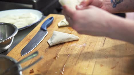 toma manual de un chef pintando un huevo lavado en la masa y cerrando la comida