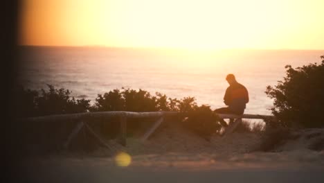 Toma-En-Cámara-Lenta-Del-Hombre-Viendo-La-Puesta-De-Sol-Frente-A-La-Vista-Del-Mar,-Cádiz,-España