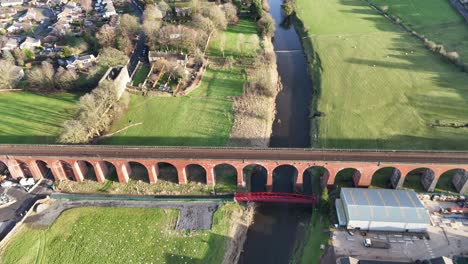 aerial footage of a lush rural landscape in the uk, showcasing serene rivers, green pastures, and quaint villages under a clear blue sky, captured in golden hour light