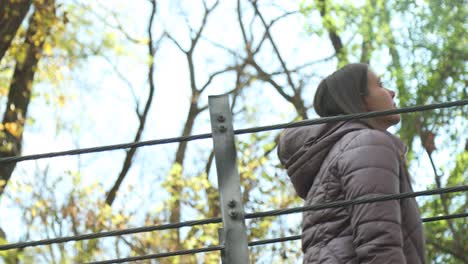 close up of a pretty girl in a purple warm cozy jacket walks across a suspension bridge during the autumn season and explores in wonder