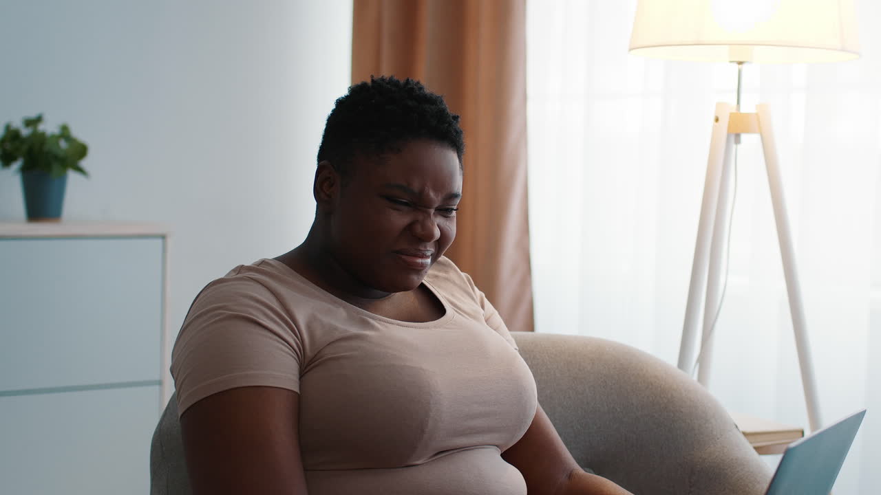 Woman appearing unhappy while using a laptop at home