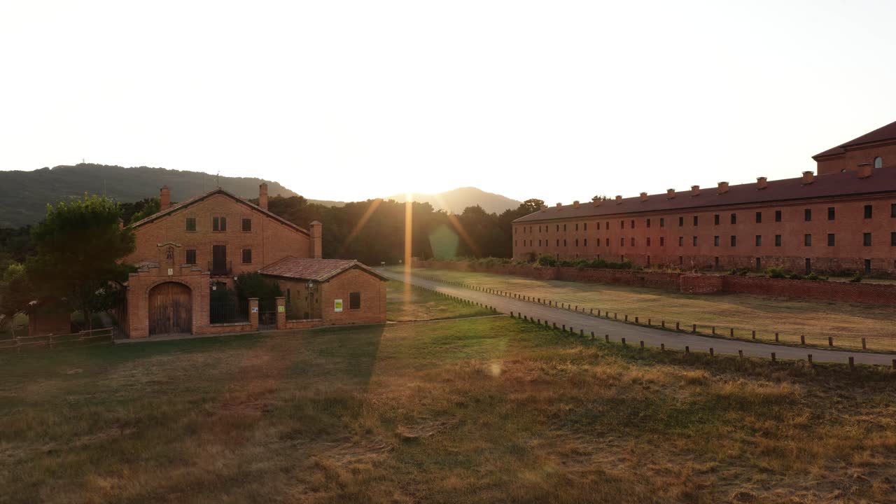 Tramonto nell'ora d'oro su edifici storici in mattoni e campo rurale