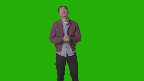 portrait of casually dressed smiling young man wearing jacket against green screen