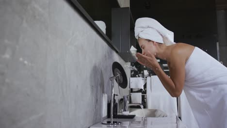 Caucasian-woman-washing-face-in-hotel-room