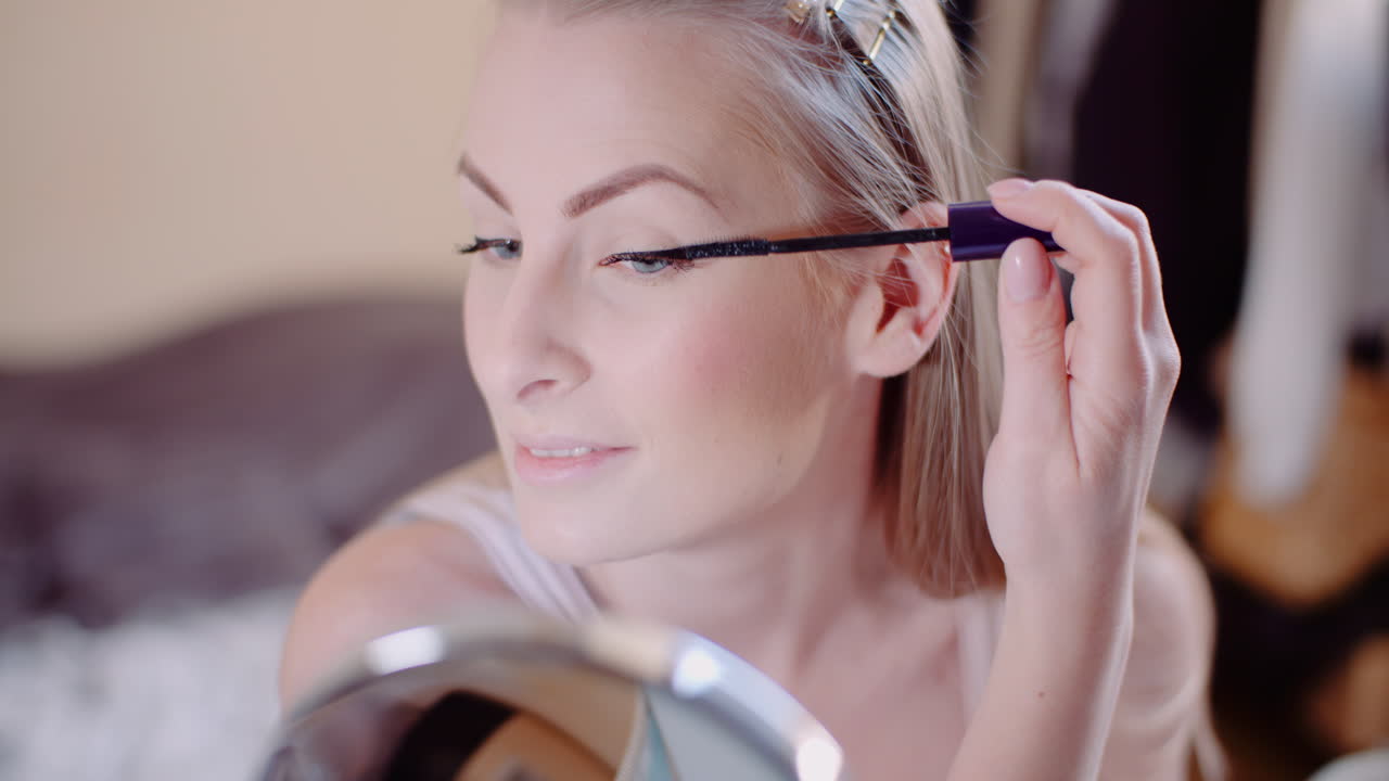 mujer maquillándose pintando pestañas con rímel 12