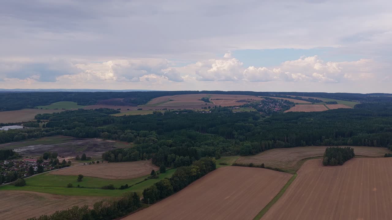 Czech landscape full of forests and rich fields from an aerial view. Horizon of clouds
