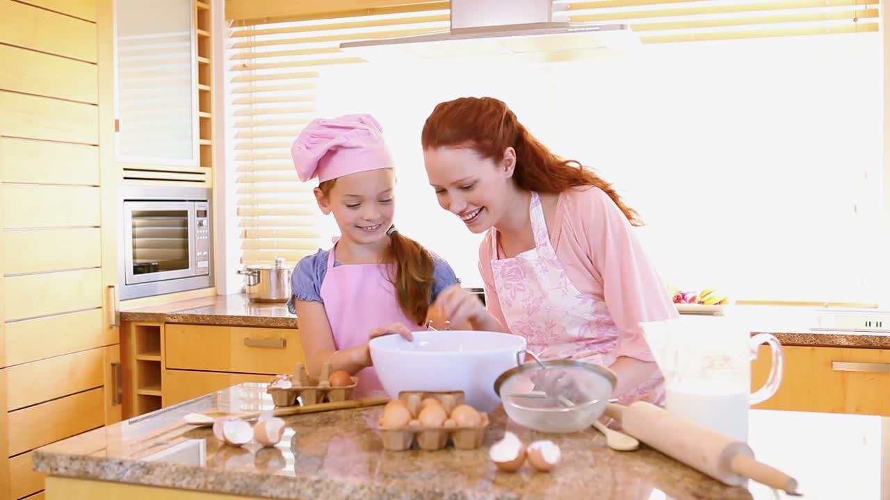 Ibu dan anak perempuan tersenyum memasak