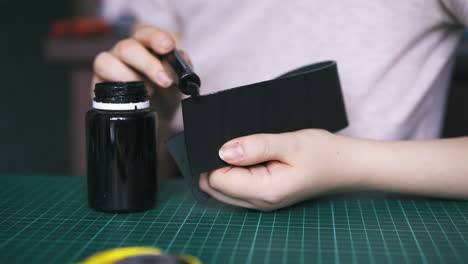skilled tailor colours black leather strip edges with pen