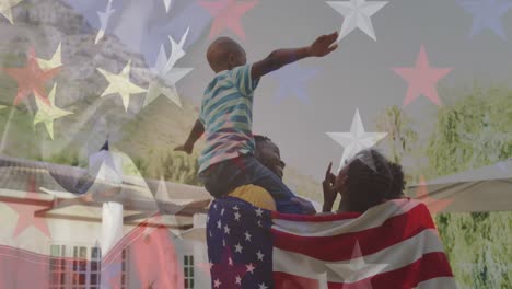 Design-Der-Amerikanischen-Flagge-Gegen-Ein-Afroamerikanisches-Paar,-Das-In-Eine-Amerikanische-Flagge-Gehüllt-Ist-Und-Seinen-Sohn-Trägt