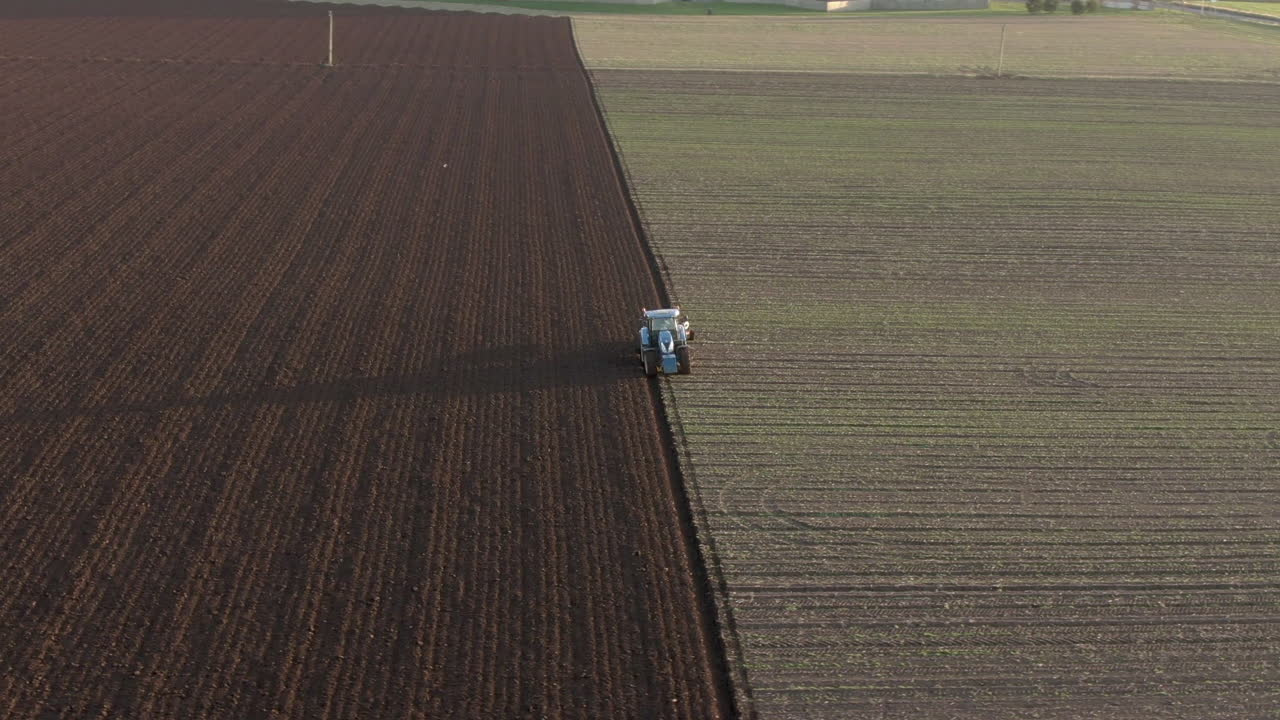 Vista aerea di un trattore agricolo che ara un campo ad Aberdeenshire in una giornata di sole, Scozia