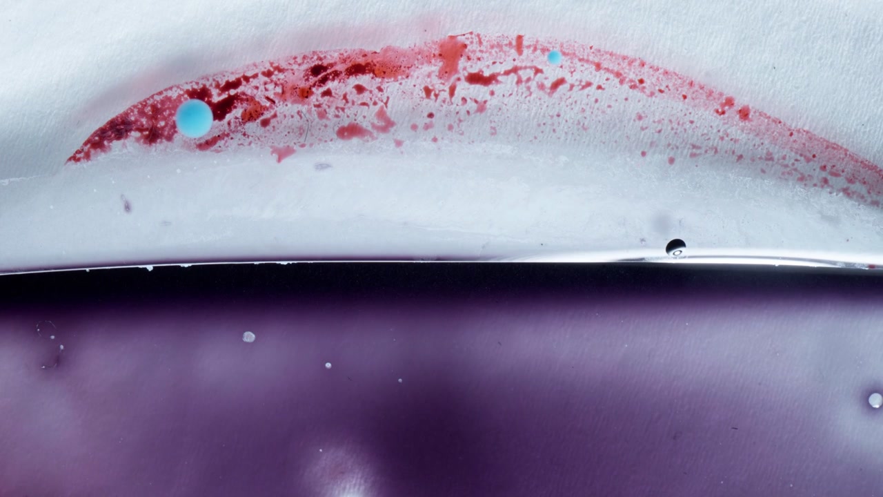 Minimalist wave of red and purple alcohol ink creates a fluid abstract on a white surface. Cinematic macro view capturing organic color mixing for relaxation and science backgrounds.