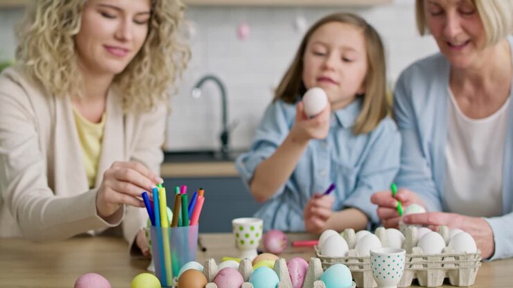 Tilt up video of girl painting Easter egg with family