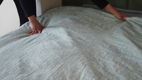 a person making a bed in a bedroom