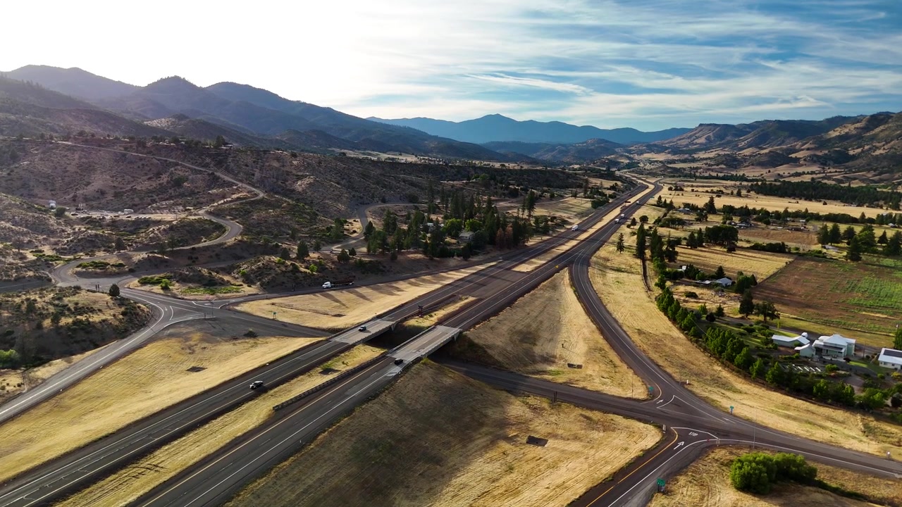 An aerial view from a drone showing a US highway cutting through vast countryside during a brilliant sunset