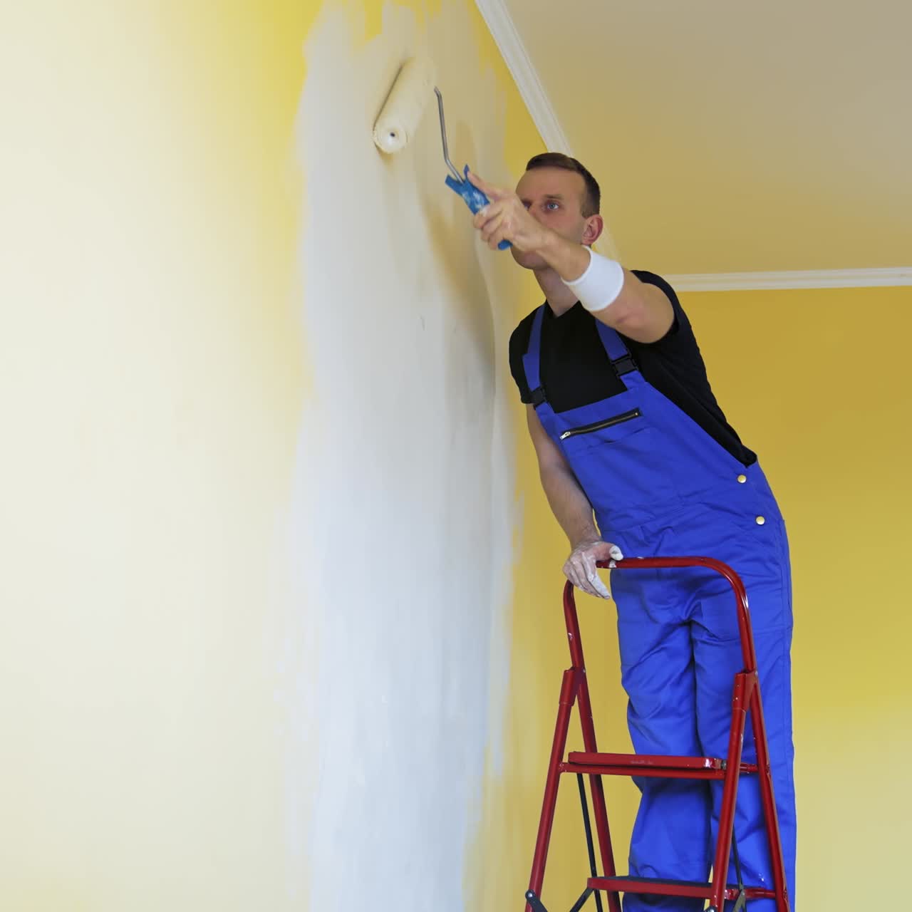 Man paints walls in apartment. Caucasian man paints the wall with roller