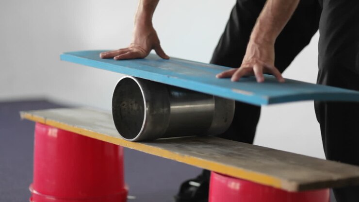 A man balances on a board set on top of a roller