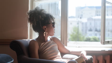 Side-view-of-fashionable-african-woman-sitting-on-armchair