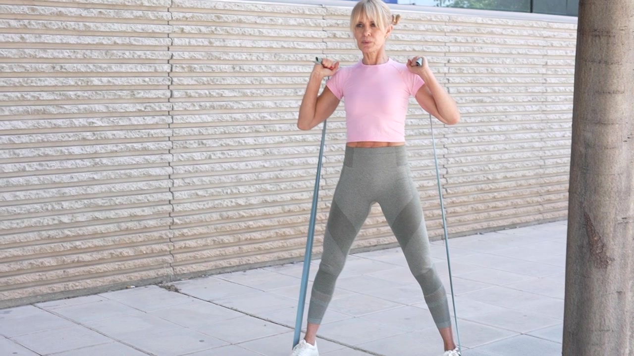 Una donna si allena all'aperto con una fascia di resistenza per concentrarsi su fitness e benessere.