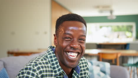 portrait of confident smiling man relaxing on sofa at home in lounge dining room