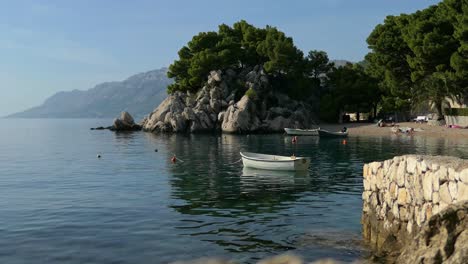 Picturesque-calm-Mediterranean-beach-bay-with-boats-by-mountain-cliffs