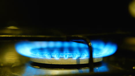 lighting gas burner on oven stovetop with blue flames, close up