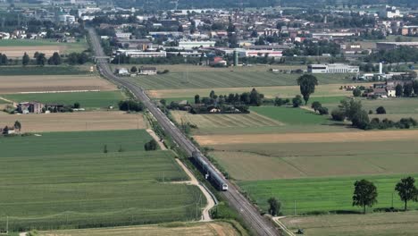 aerial shot of a train in the middle of the countryside towards the city in the po valley - italy