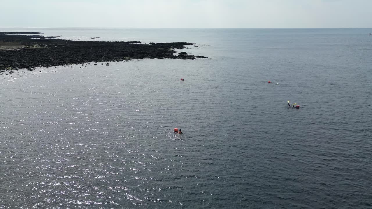 Drone aerial view in South Korea countryside flying over the sea rocky area shallow area big building haenyeo women divers fishing jeju island