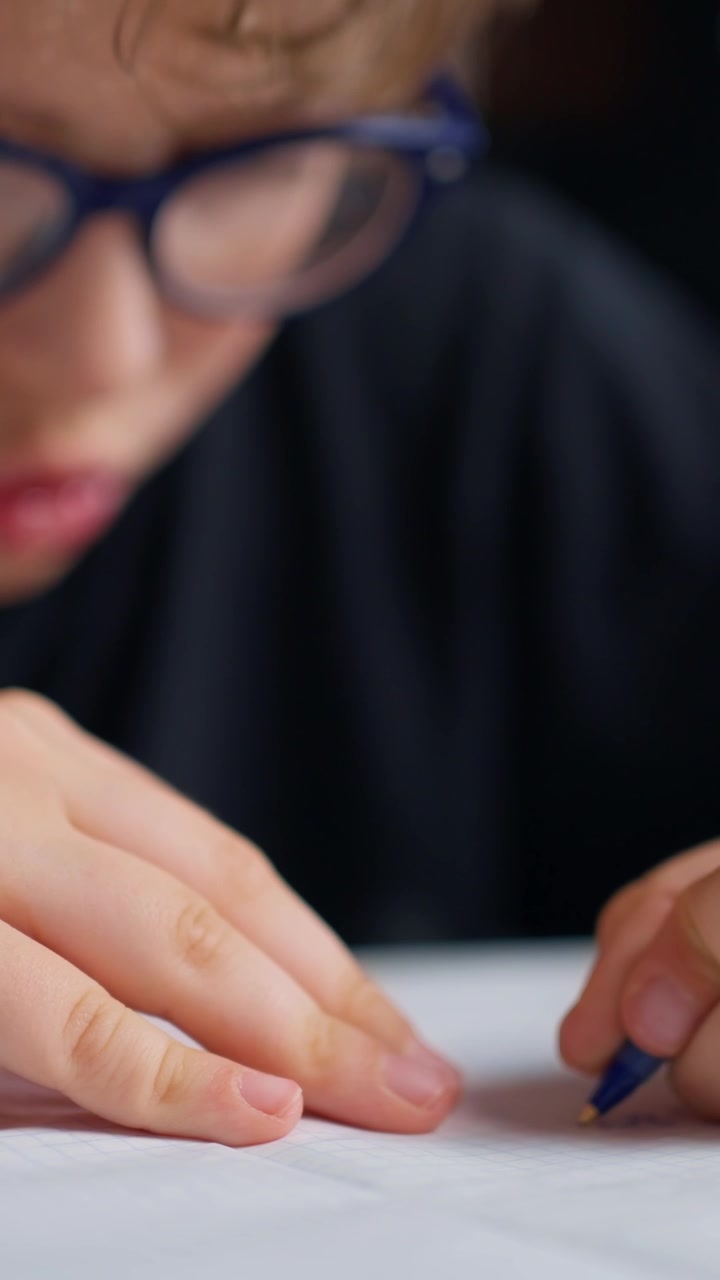 Bambino con gli occhiali che scrive e controlla l'ora sullo smartwatch