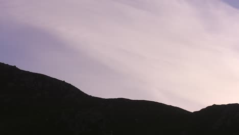 Golden-hour-shot-of-a-plane-cutting-across-the-silhouette-of-a-cliff-near-Dalmore-beach-in-Carloway