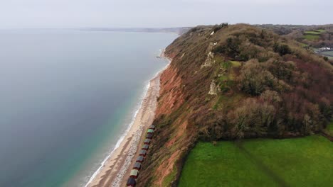 glatte 4k-luftaufnahme, die hoch über den bergen und sanften hügeln des britischen branscombe-strandes fliegt und einen blick auf das wunderschöne blaue meer erhascht