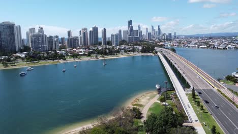 Fliegen-über-Eine-Bucht-Und-Eine-Brücke-In-Richtung-Wolkenkratzer-Und-Einer-Großen-Stadt