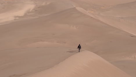 Hombre-Caminando-Sobre-Dunas-De-Arena-En-Un-Día-Soleado