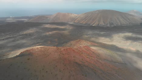 panning up drone shot of a red volcano by the ocean on a cloudy day