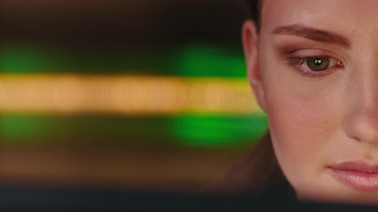 Close-up of Young Woman Focused on Computer Screen in Dark Office
