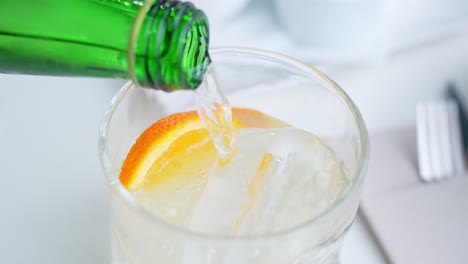 Soda-In-Glas-Mit-Eis-Und-Orangenscheibe-Gießen,-Nahaufnahme