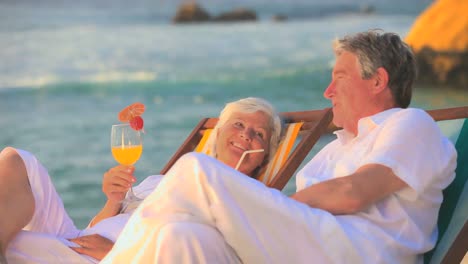 mature couple drinking cocktails on the beach