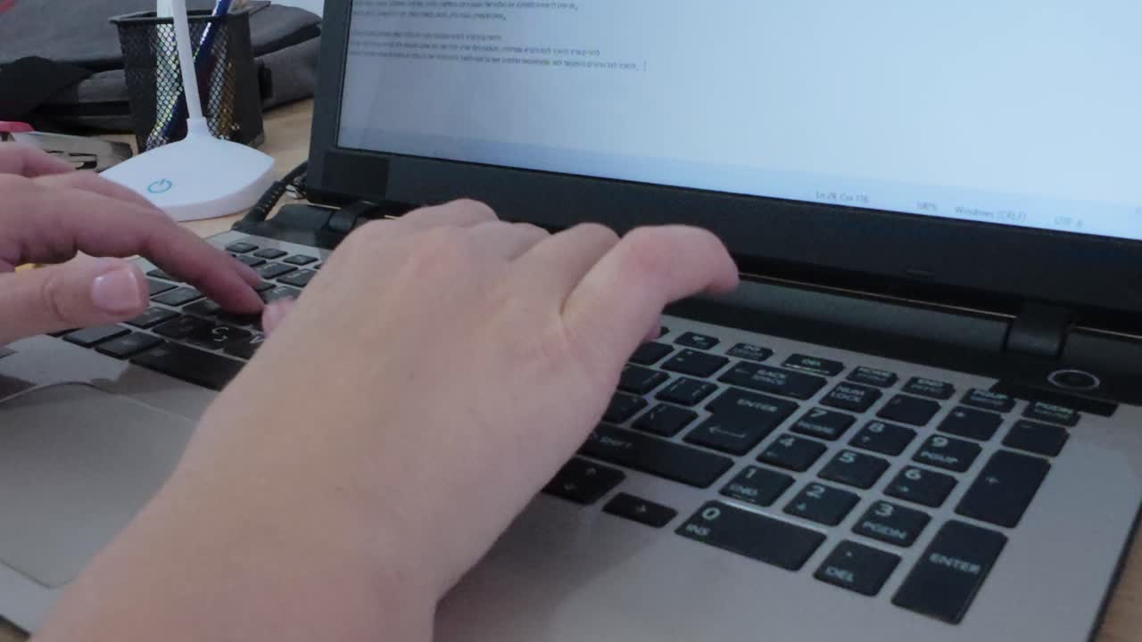 Detailed close-up view of hands interacting with a laptop keyboard, fingers pressing keys