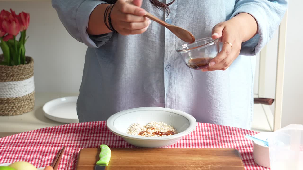 건강 한 아침 식사 를 준비 하고 있는 여자 는 그라놀라 에  을 첨가 하고 있다