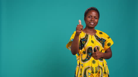 Cheerful-positive-woman-showing-thumbs-up-gesture-in-studio