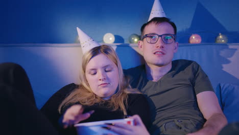 couple watching movie at home with party hats